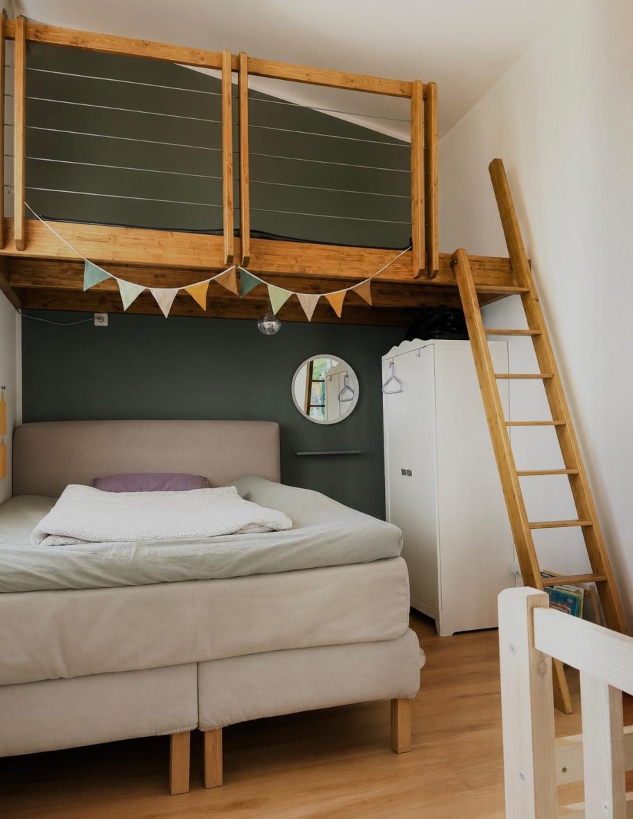 Helles Schlafzimmer mit Hochbett, Leiter, minimalistischem Design und runder Wandspiegel.