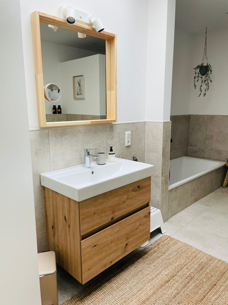 Moderne Badezimmeransicht mit Holzwaschtisch, Spiegel und Badewanne.