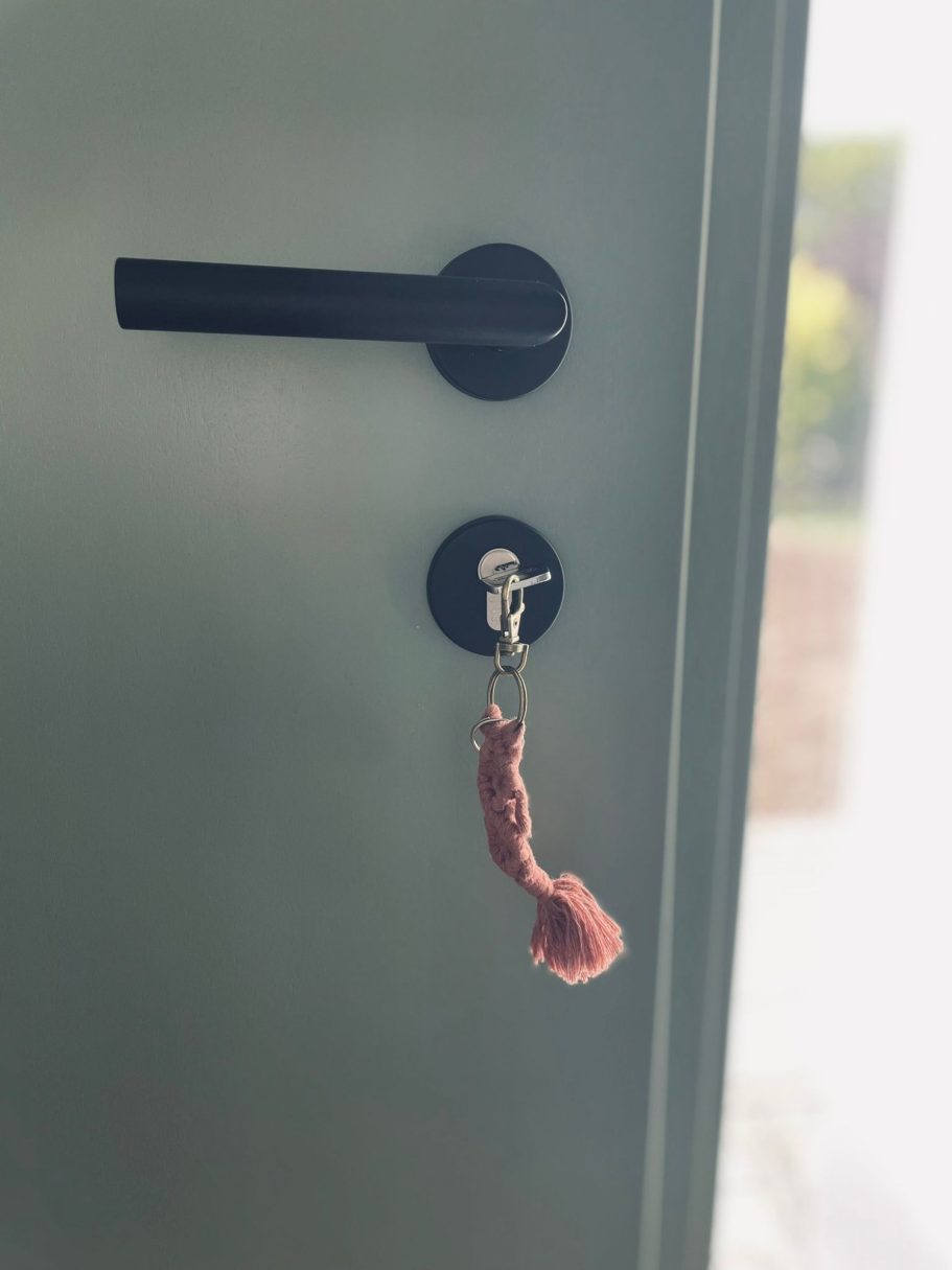 Schlüssel mit pinkem Anhänger hängt an einem schwarzen Türschloss.