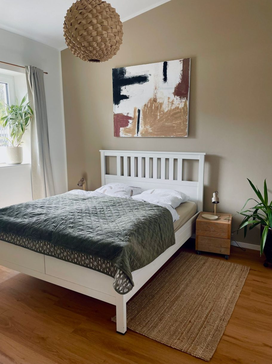 Helle Schlafzimmer mit Doppelbett, Kunstwerk an der Wand und Pflanzen.