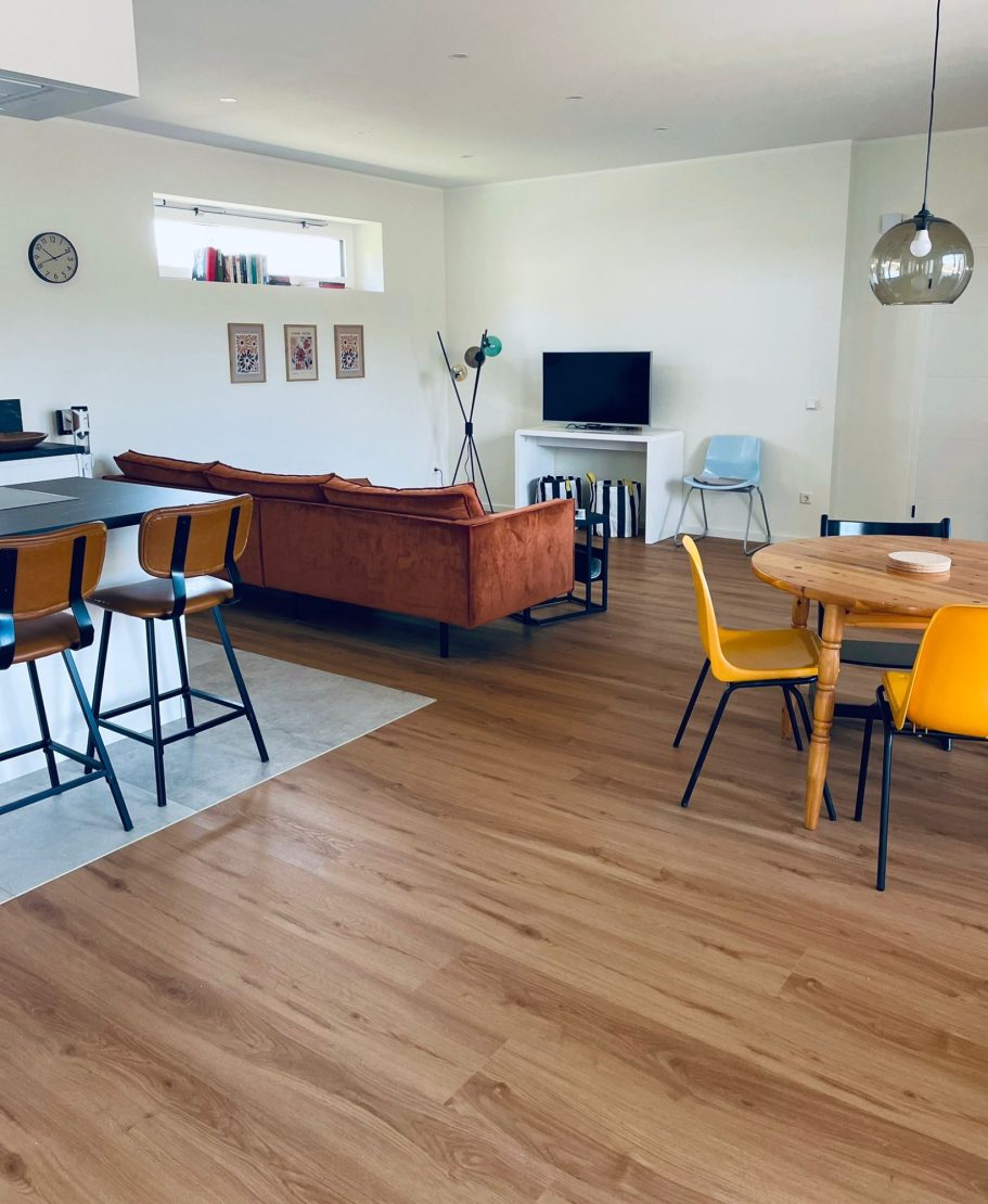 Helles Wohnzimmer mit Sofa, TV, Esstisch und Stühlen in modernem Design.